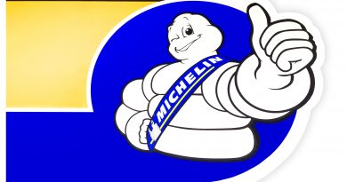 Logo maskota Michelin na modrém a žlutém pozadí s palcem nahoru.