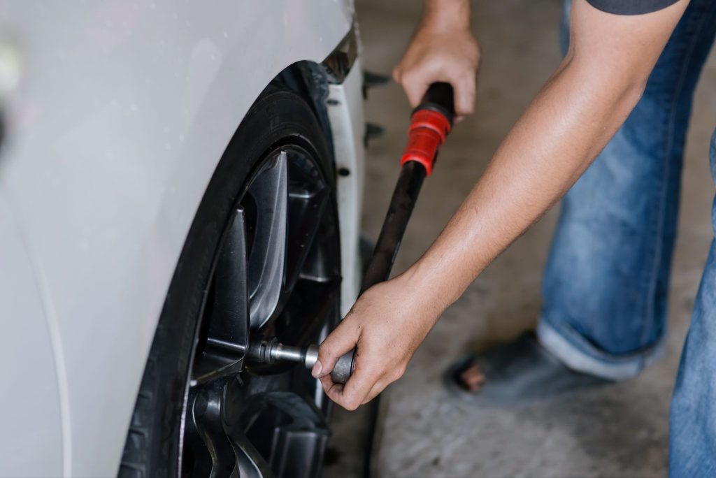 Muž utahuje kolo osobního automobilu. 